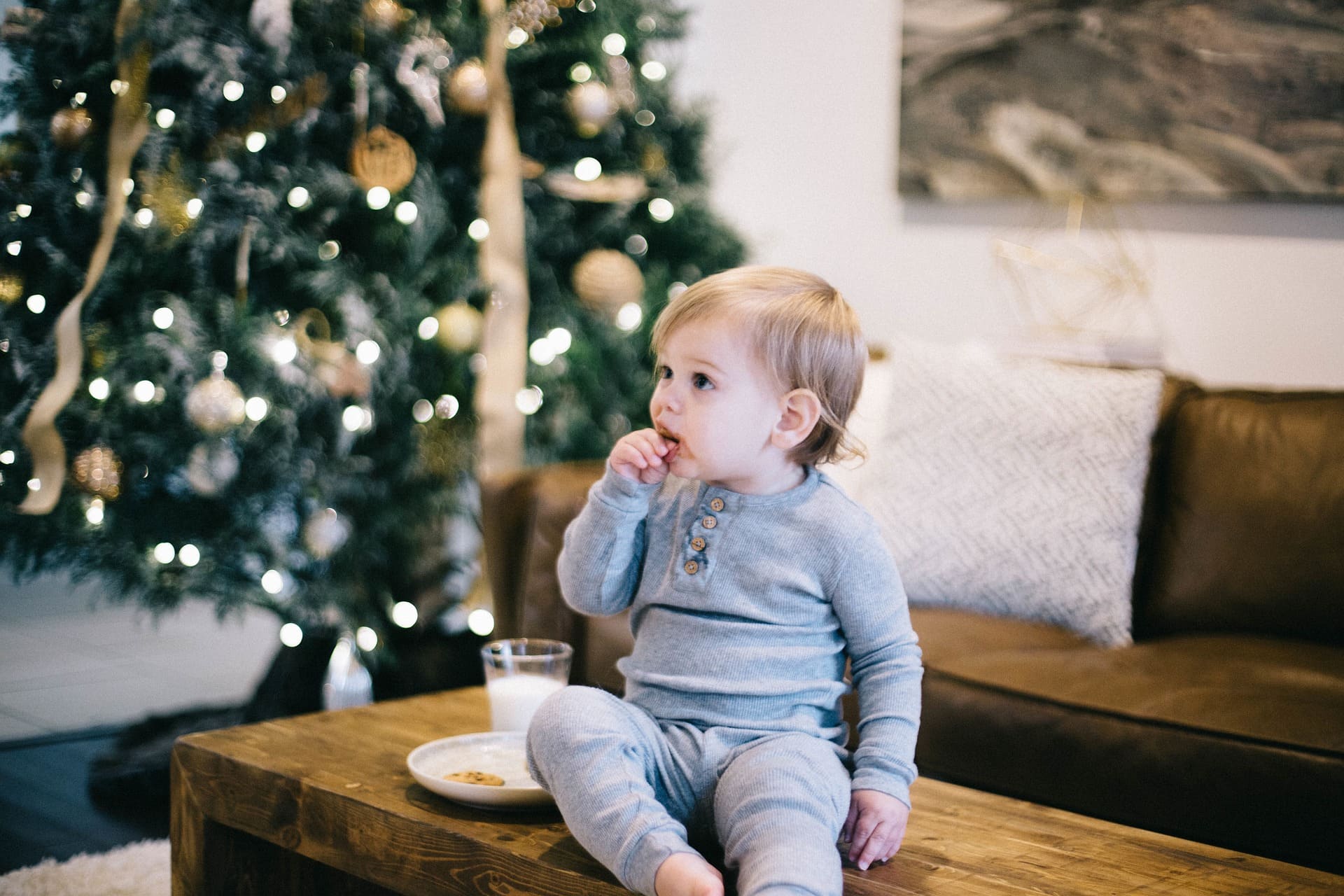 Niño en sofá frente a árbol de Navidad